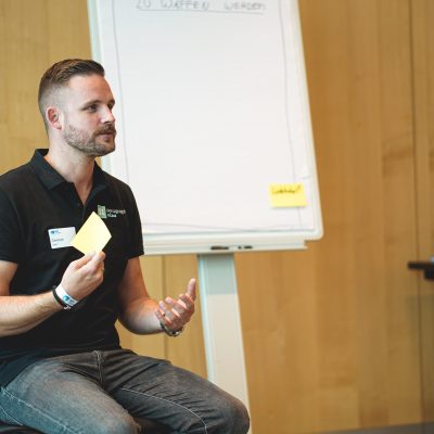 Christian Klein Agile Coach sitzt vor einem Flipchart mit einem Post-It in der Hand