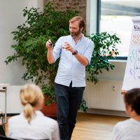 Alexander Kylburg von paragraph eins am Flipchart und spricht motiviert zu einer Gruppe