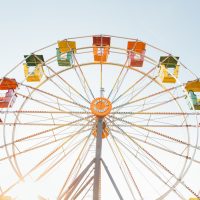 Ein buntes Riesenrad auf einer Kirmes hat offene Gondeln in vielen verschiedenen Farben.