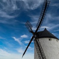Eine alte gemauerte Windmühle steht vor einem blauen wolkendurchzogenen Himmel